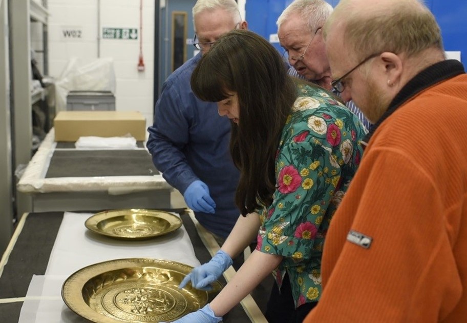 Staff members cleaning some of the brass objects