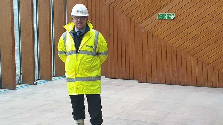 Burrell worker wearing a hard hat and high visibility jacket visits the project build site